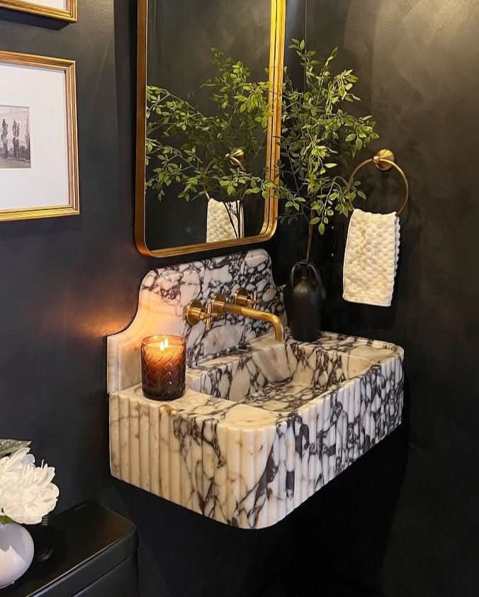 Calacatta Viola marble sink against dark walls with aged brass fittings