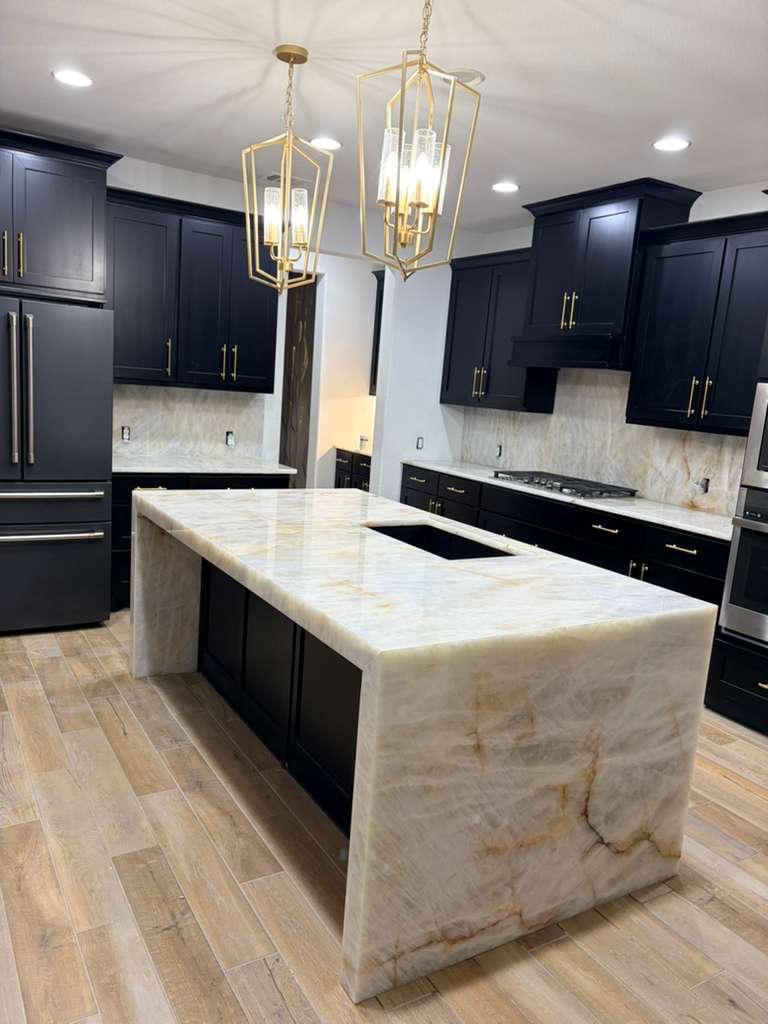 Cristallo quartzite waterfall island with dark navy cabinetry and brass lighting