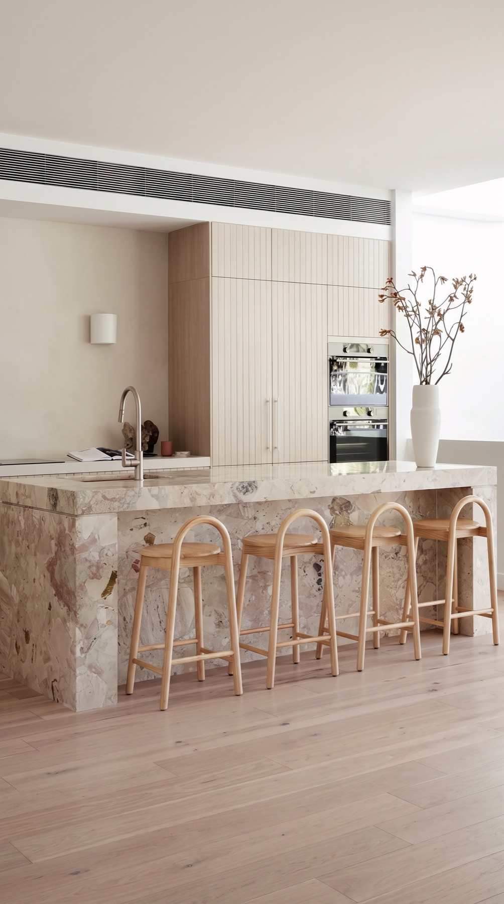 Bright contemporary kitchen with a Breccia Botticelli marble waterfall island and matching stone surfaces