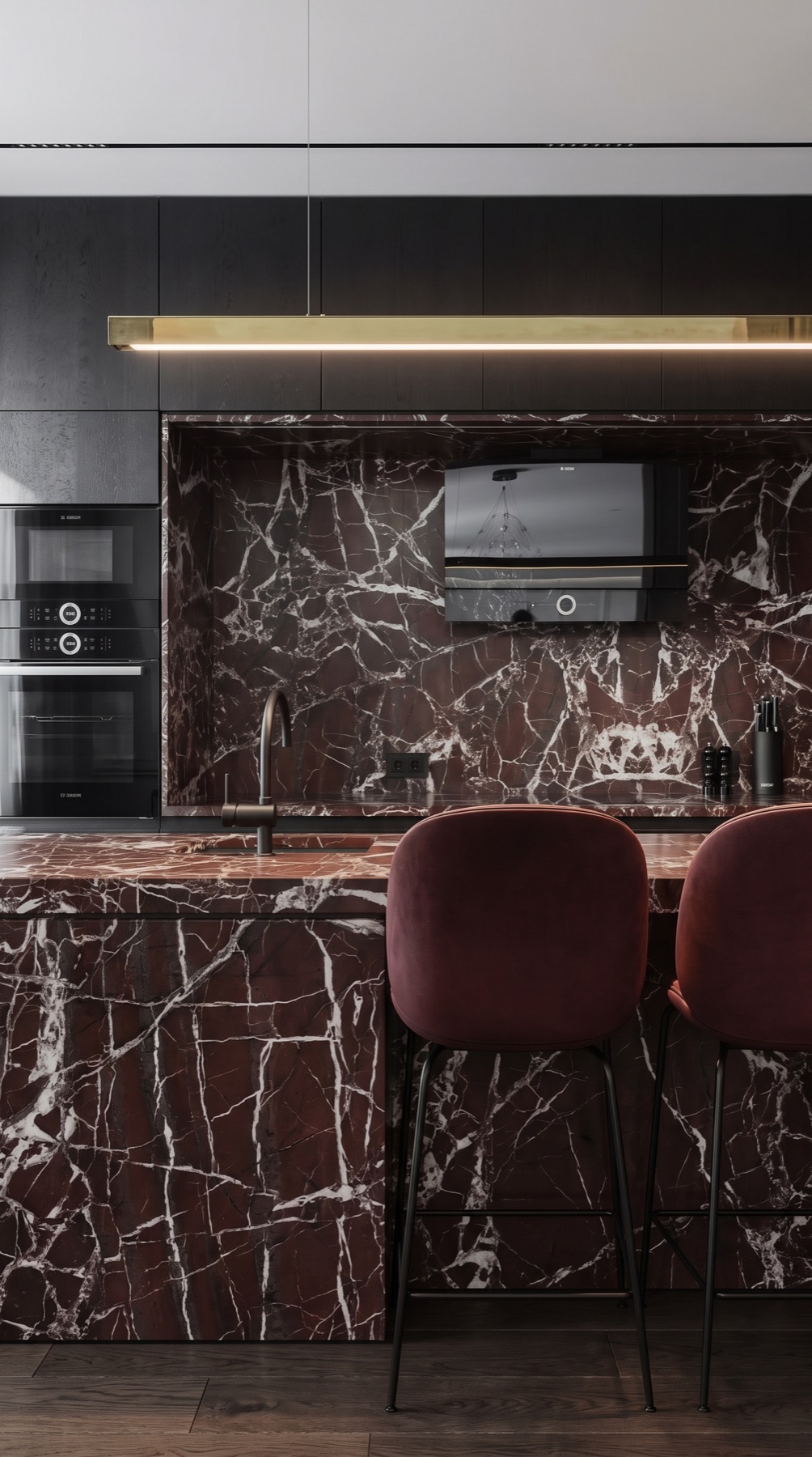 Rosso Levanto Italian marble kitchen with deep burgundy counters, backsplash, and waterfall island beside black cabinetry