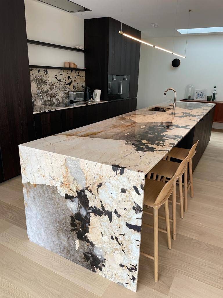 Patagonia natural stone waterfall island and backsplash in a modern black kitchen