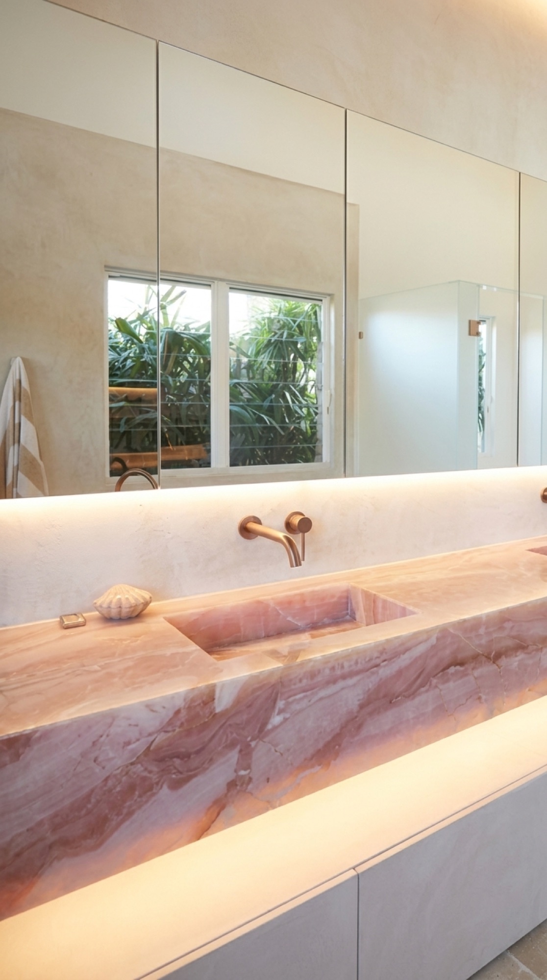 Backlit pink onyx integrated bathroom sink glowing above white cabinetry