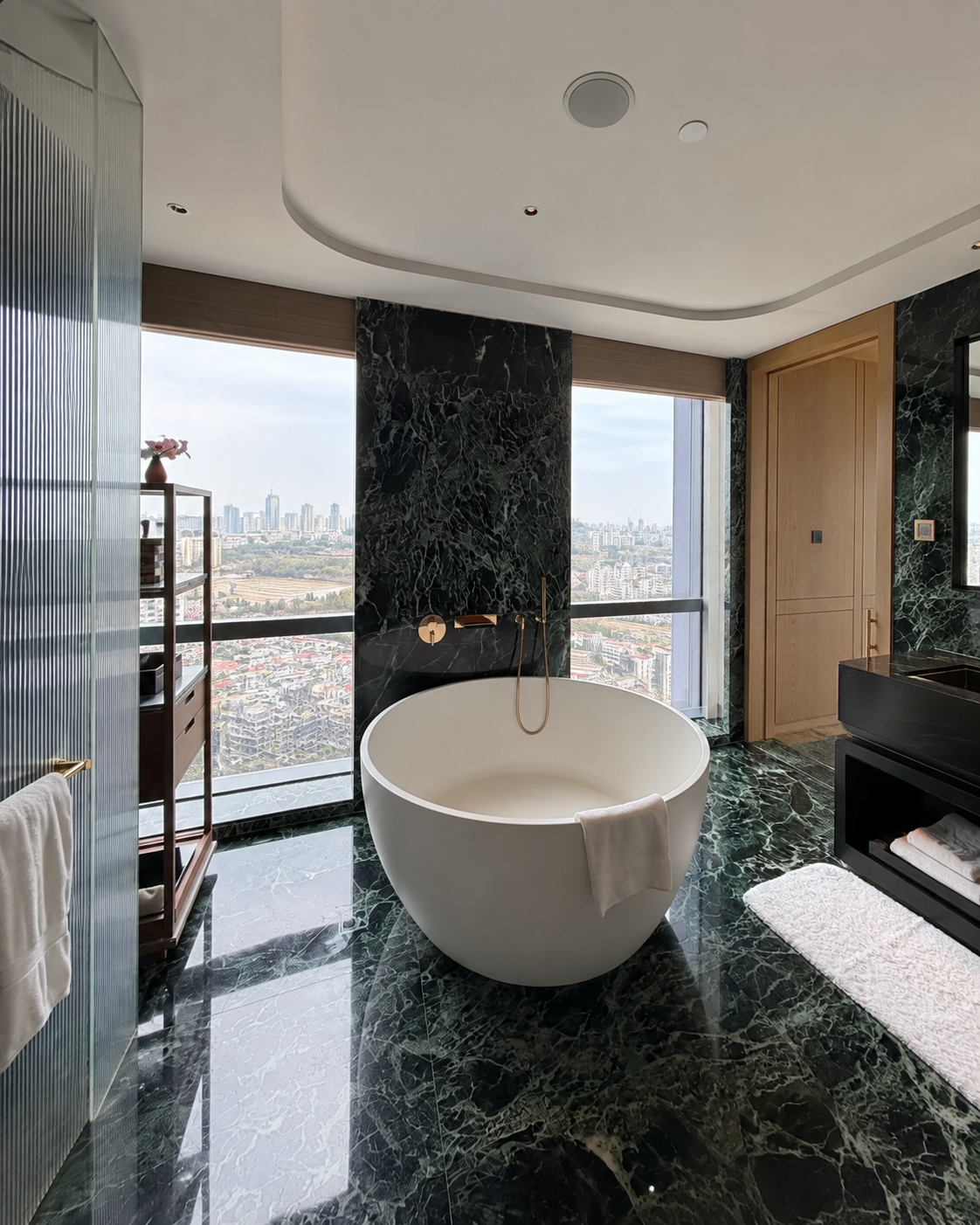 Verde Alpi Italian green marble bathroom with a freestanding tub, dark green floor and wall cladding, and brass fittings